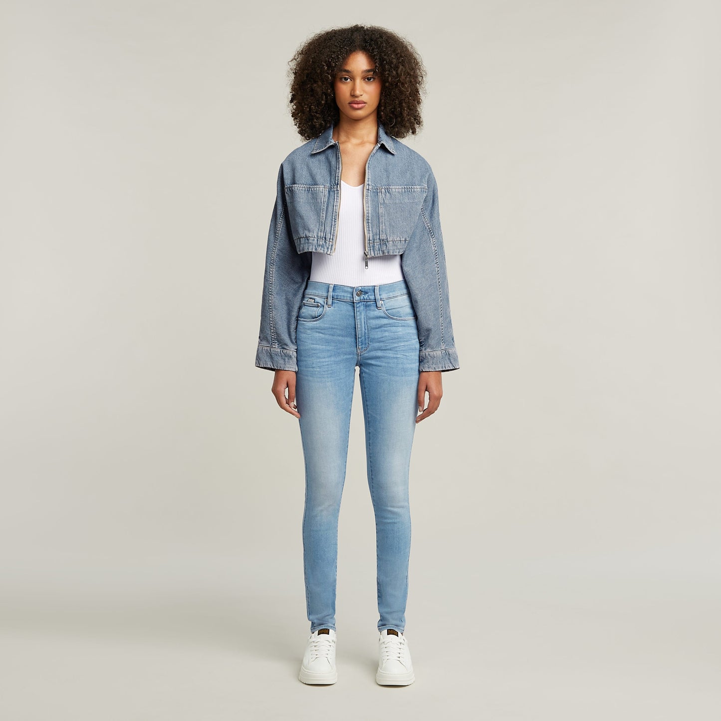 Mujer luciendo jeans 3301 skinny, de corte pitillo en tono azul claro, combinados con chaqueta de mezclilla.