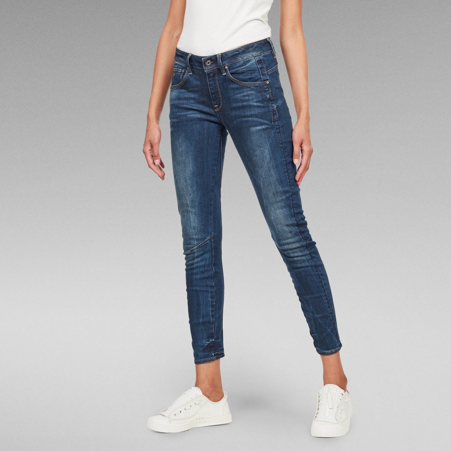 Mujer usando Jeans Arc Skinny, pitillo de denim anatómico, con costuras especiales en las rodillas.
