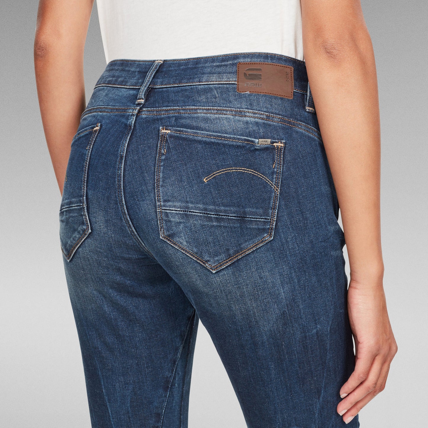Mujer usando jeans Arc Skinny, vista trasera que destaca el diseño y la etiqueta del logotipo en la cintura.