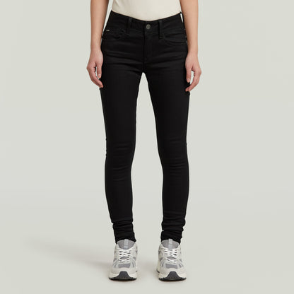 Mujer usando Jeans Lynn Super Skinny en color negro, con calzado deportivo, vista frontal.