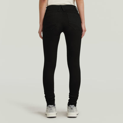 Mujer usando los jeans Lynn super skinny, mostrando la parte trasera del modelo en denim negro ajustado.