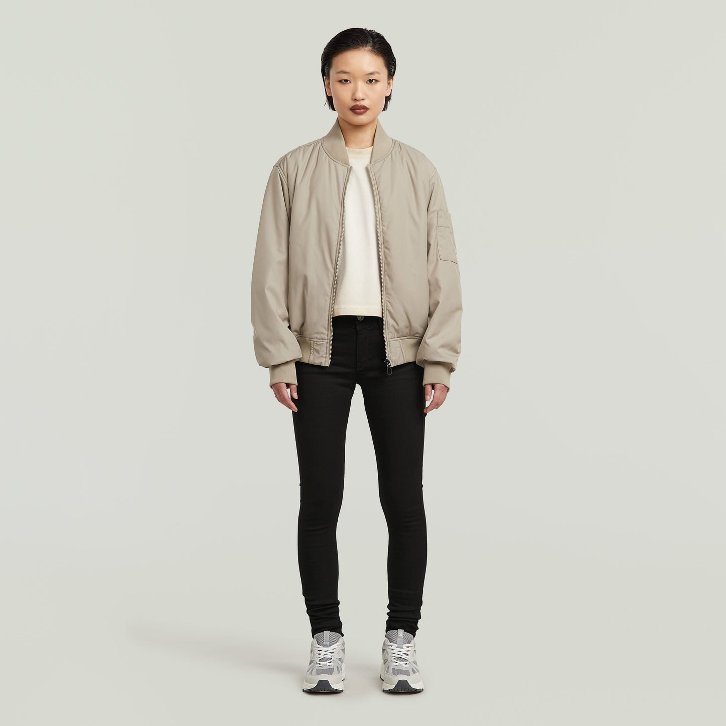 Modelo usando la chaqueta beige con los Lynn super skinny jeans y zapatos deportivos en un fondo neutro.