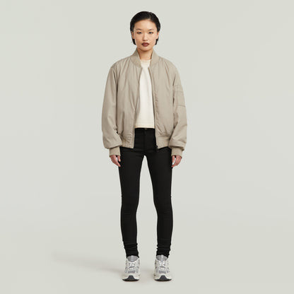 Modelo usando la chaqueta beige con los Lynn super skinny jeans y zapatos deportivos en un fondo neutro.