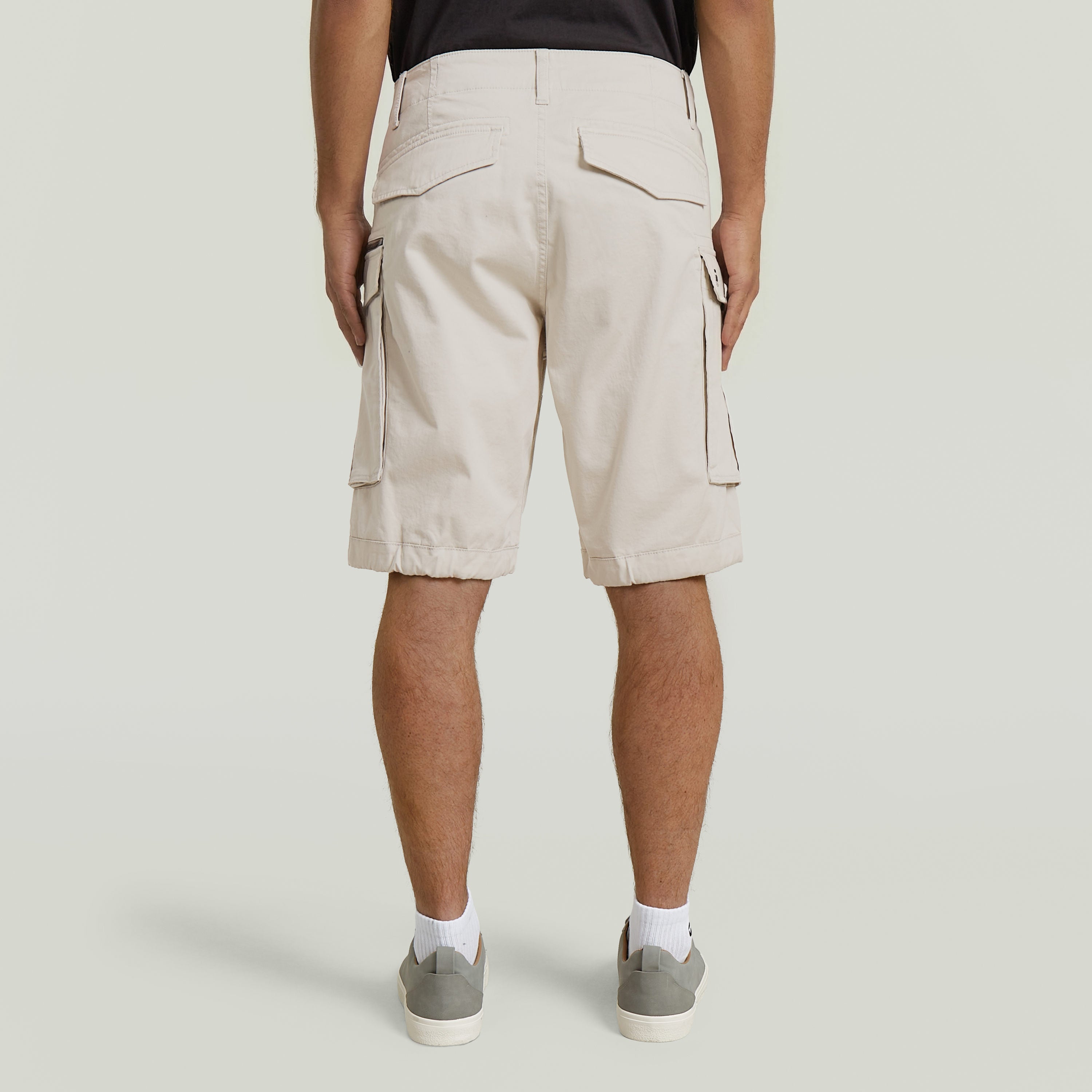 Back view of relaxed fit zip shorts in beige, featuring multiple pockets and a comfortable design.