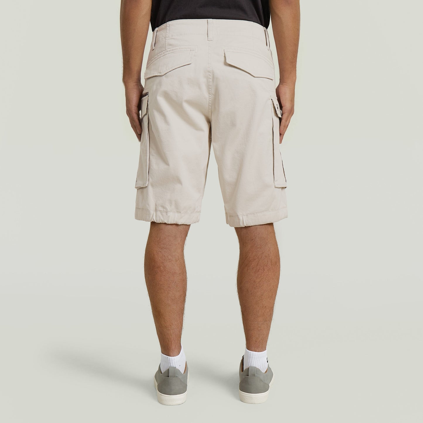Back view of relaxed fit zip shorts in beige, featuring multiple pockets and a comfortable design.
