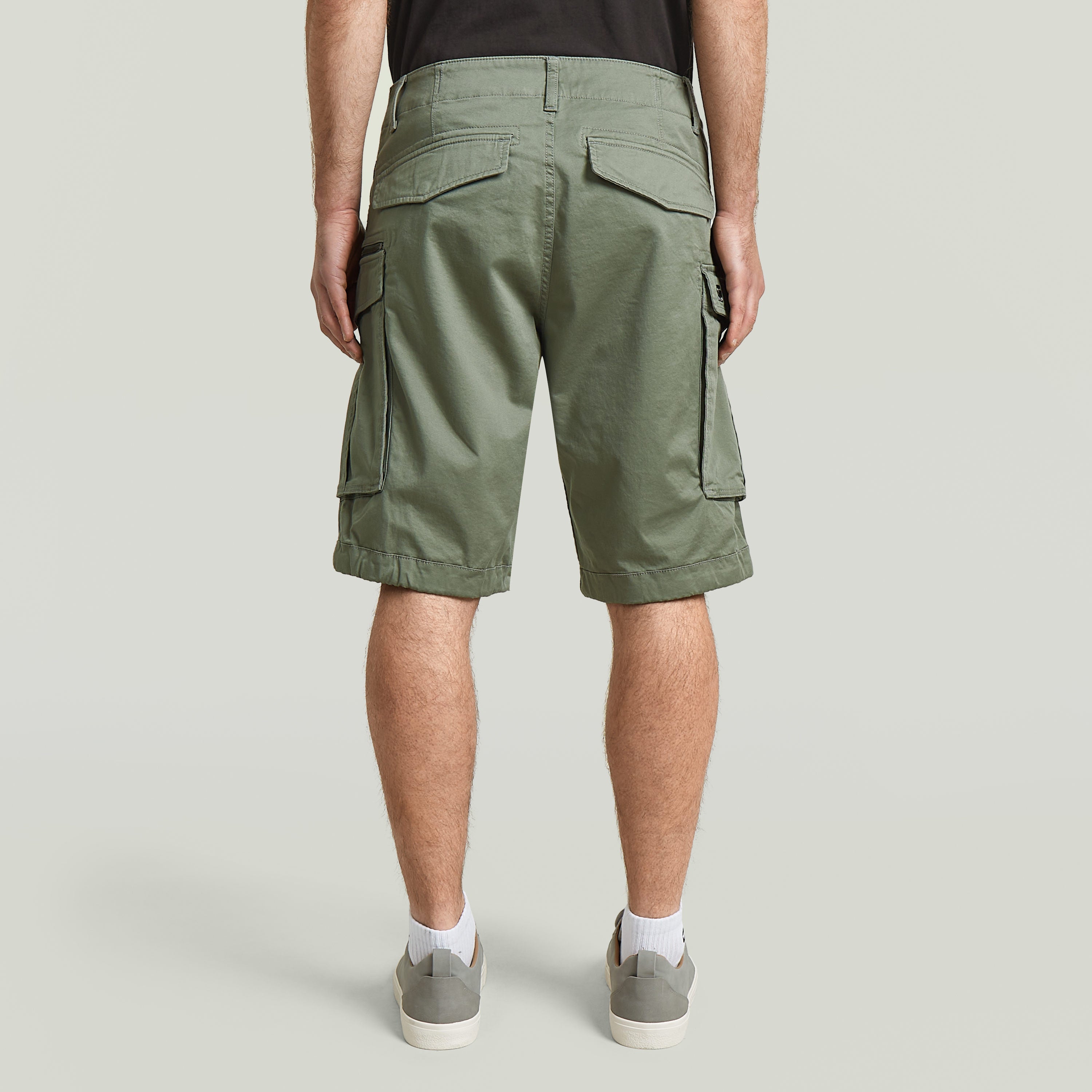 Back view of relaxed fit Rovic zip shorts in green, showcasing functional pockets and relaxed design.