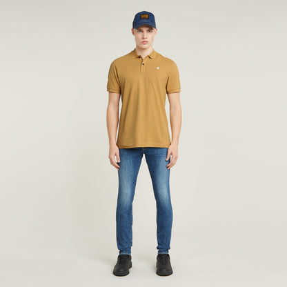Modelo usando Dunda Slim polo color mostaza con jeans, mostrando su estilo moderno y casual.
