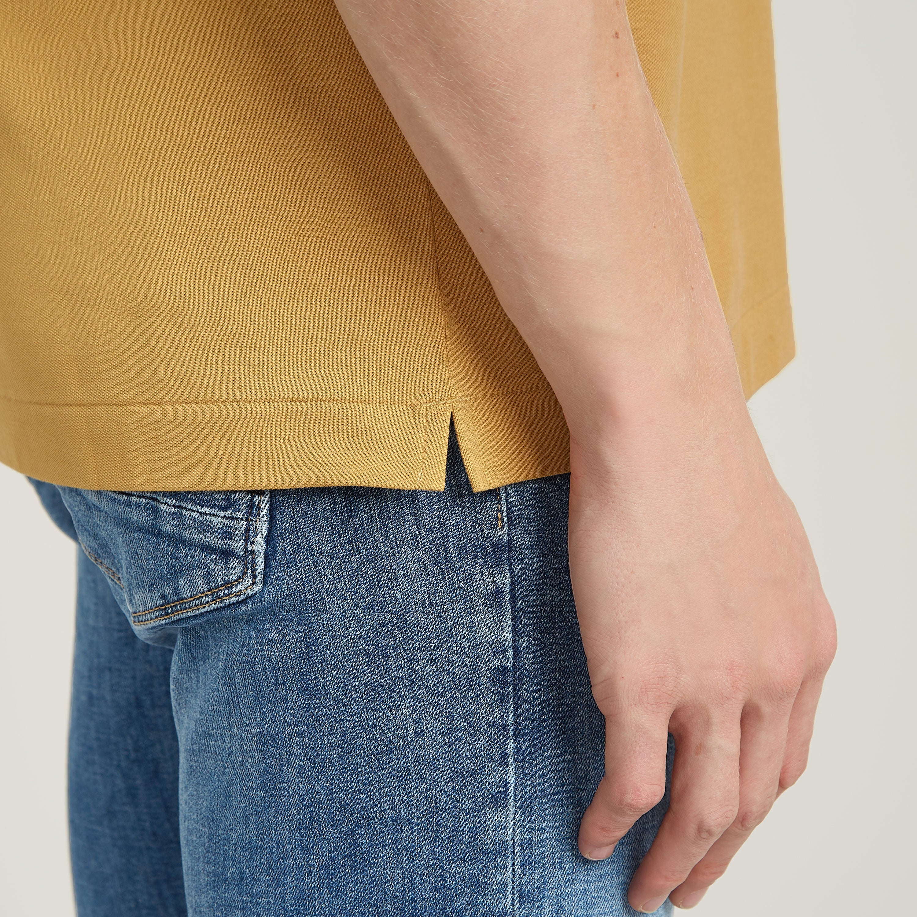 Dunda Slim polo close-up showing side slit and casual fit, highlighting the garment's design and style.