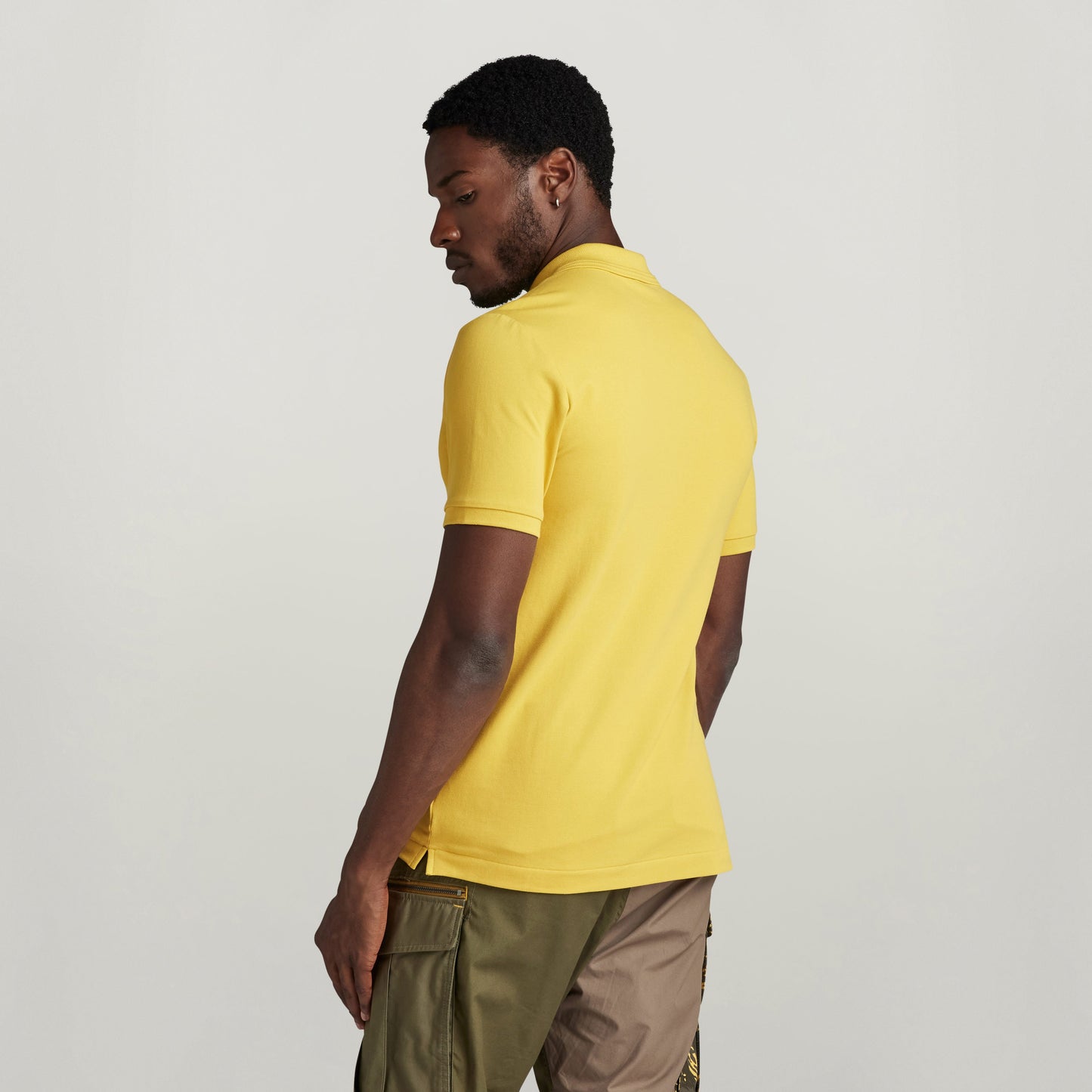 Modelo masculino mostrando el polo Dunda Slim acanalado en color amarillo, con detalles en cuello y puños.