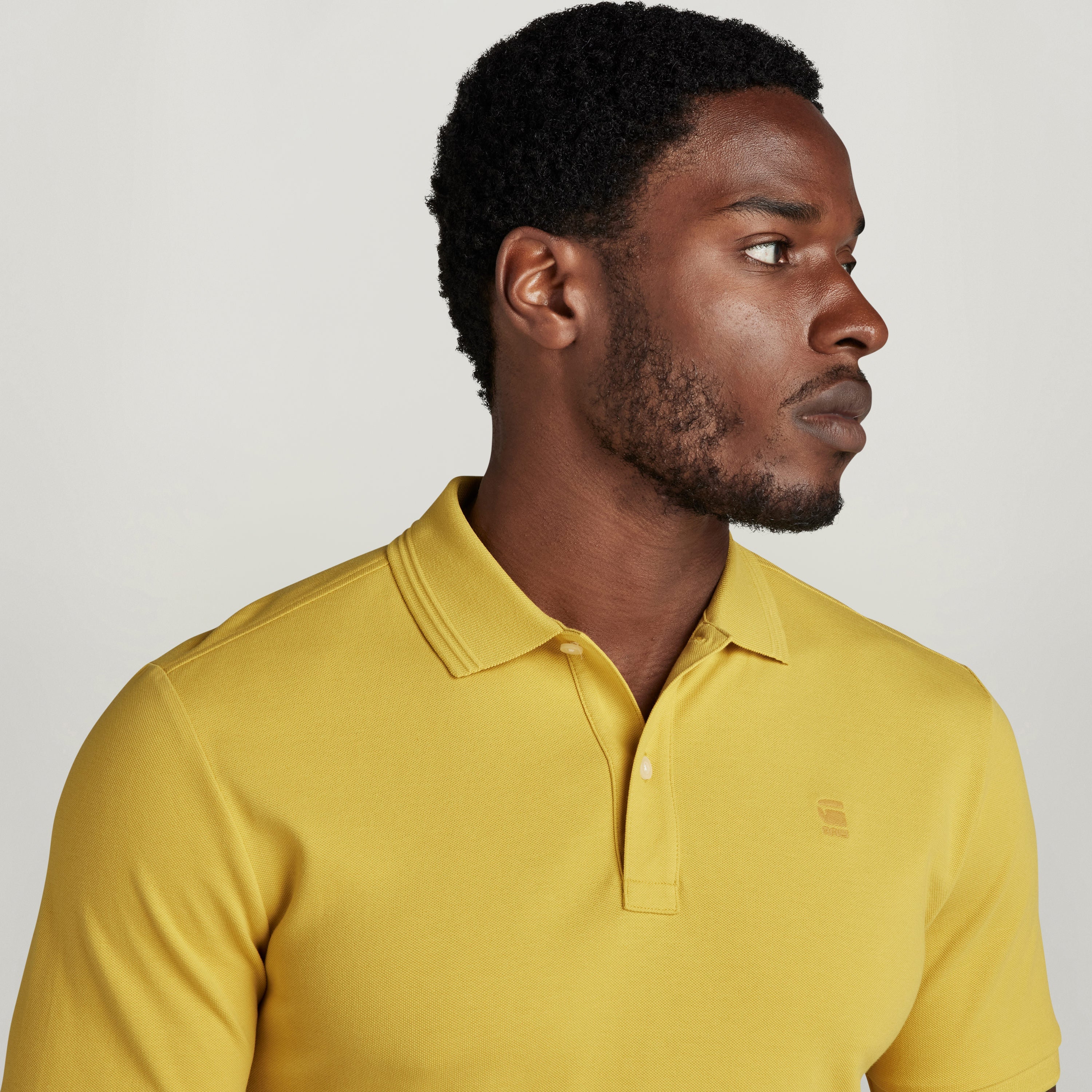 Hombre con polo Dunda Slim amarillo con diseño acanalado, mostrando cuello y puños acanalados.
