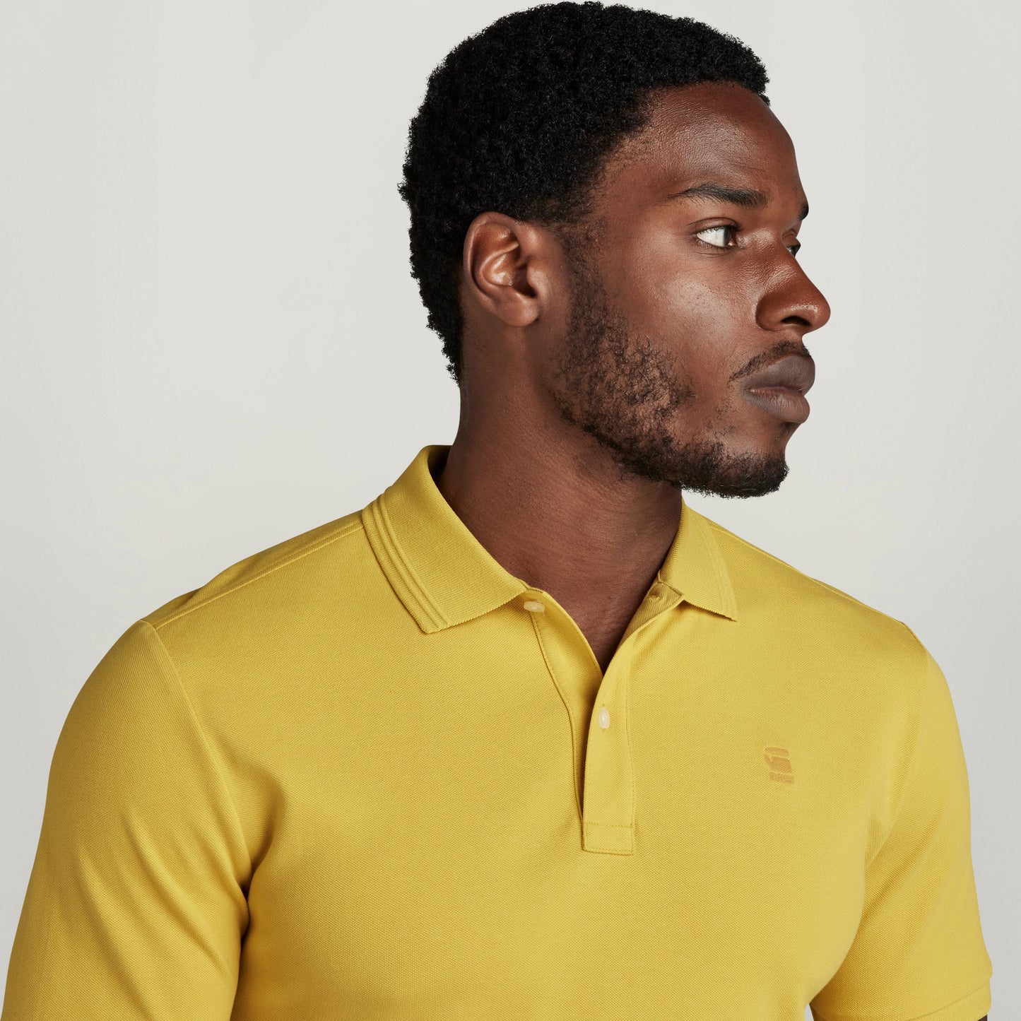 Hombre con polo Dunda Slim amarillo con diseño acanalado, mostrando cuello y puños acanalados.