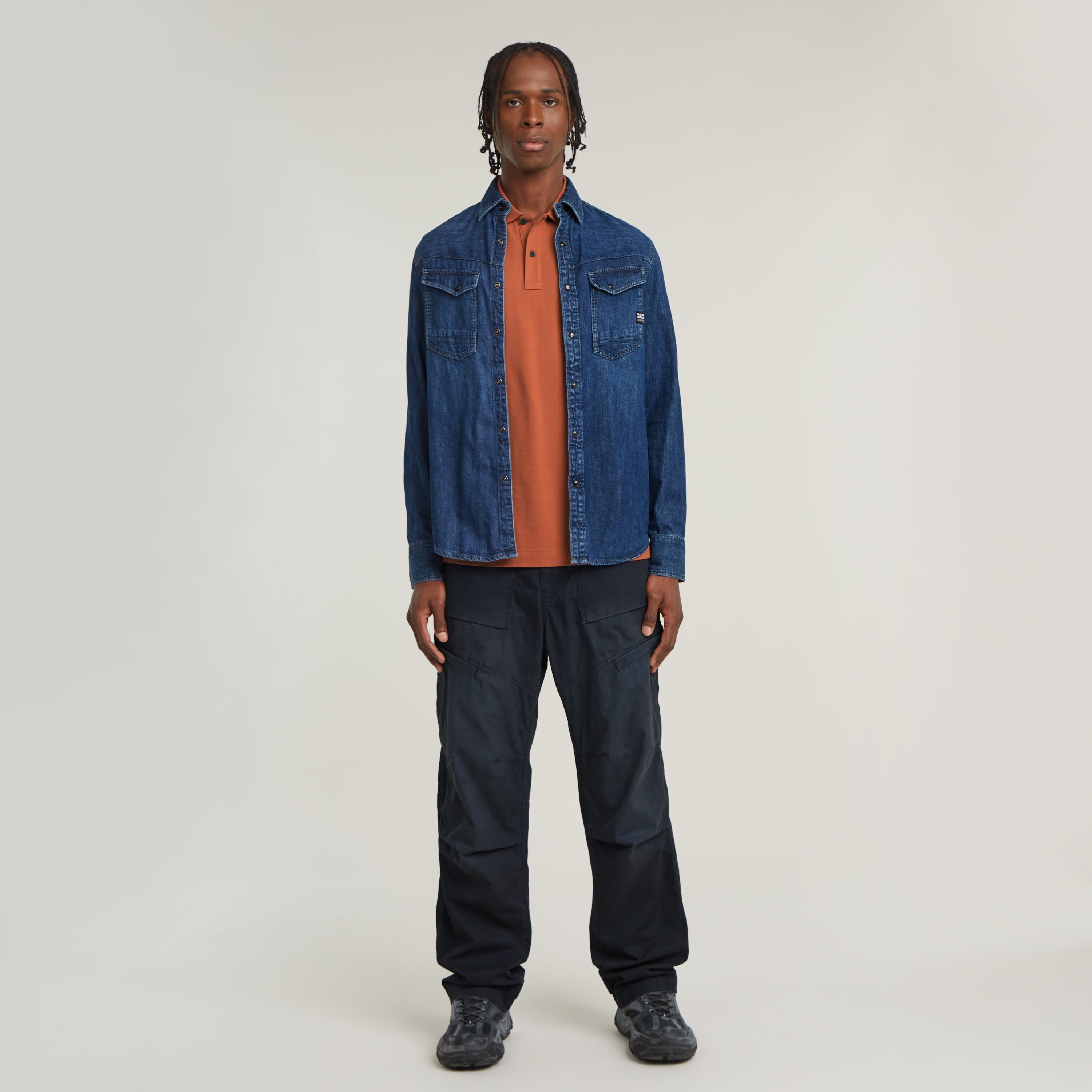 Hombre vistiendo polo Dunda Slim fit polo shirt en color naranja bajo una chaqueta de mezclilla azul.