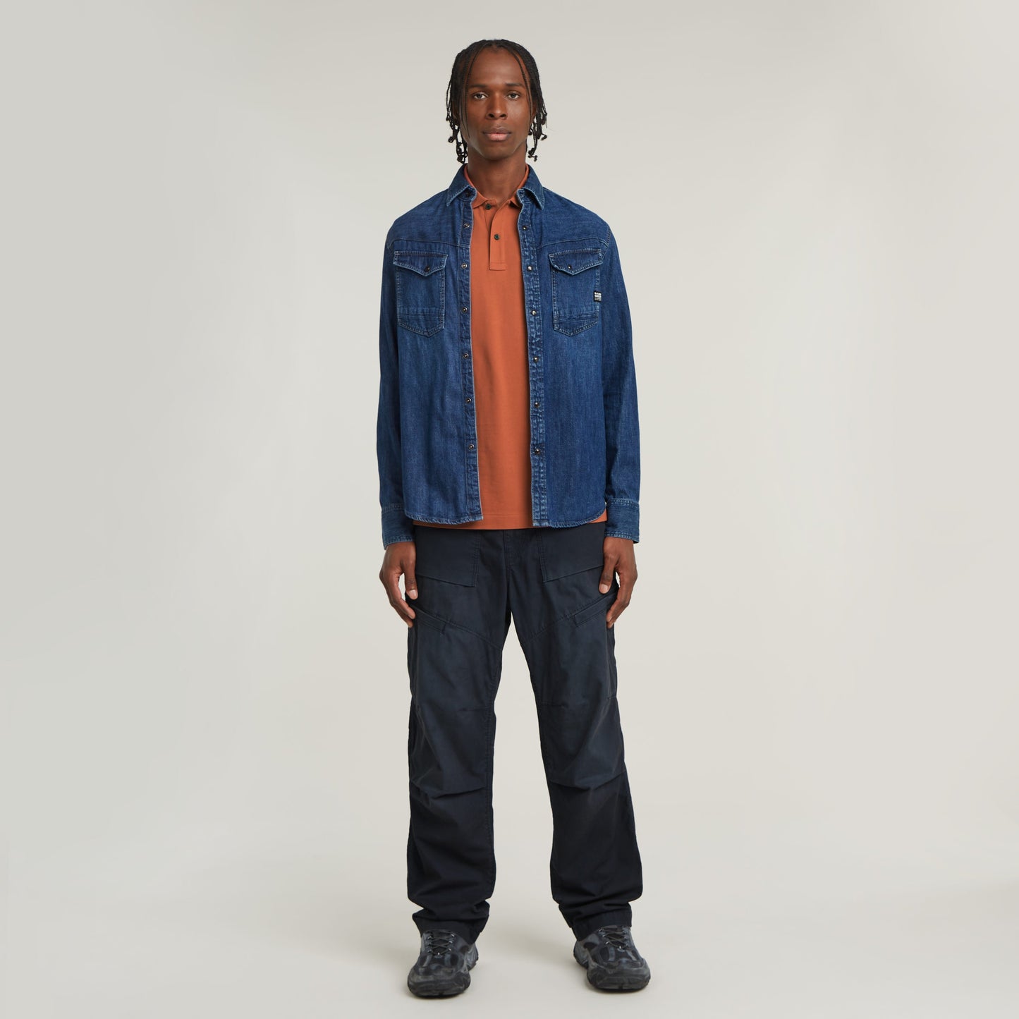 Hombre vistiendo polo Dunda Slim fit polo shirt en color naranja bajo una chaqueta de mezclilla azul.