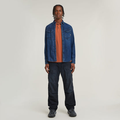 Hombre vistiendo polo Dunda Slim fit polo shirt en color naranja bajo una chaqueta de mezclilla azul.
