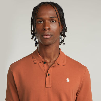 Hombre usando un polo Dunda Slim fit polo shirt en color marrón con collar acanalado y bordado en el pecho.