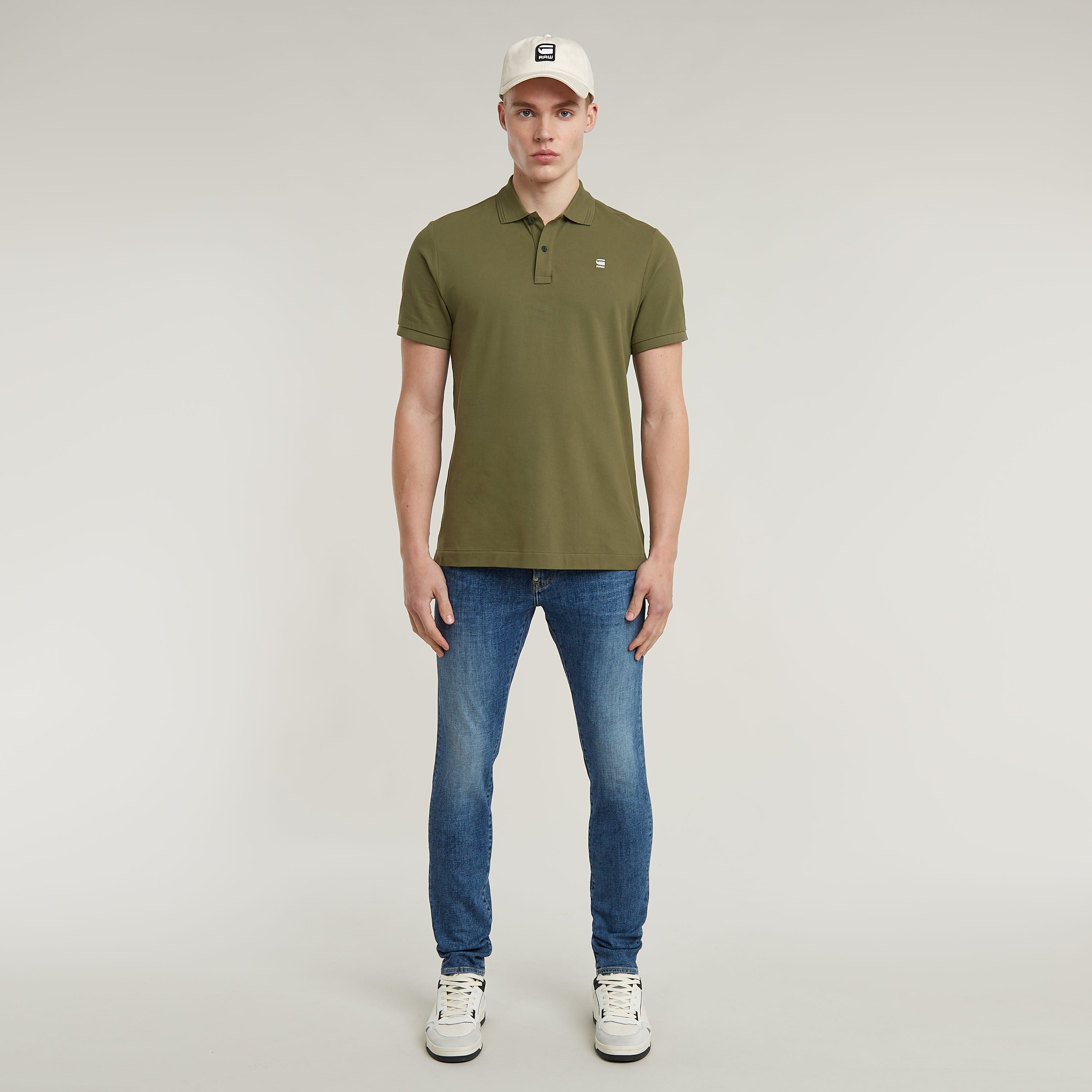 Dunda Slim Polo Shirt worn by a model featuring a green design and casual jeans with a cap.