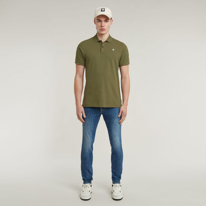 Dunda Slim Polo Shirt worn by a model featuring a green design and casual jeans with a cap.