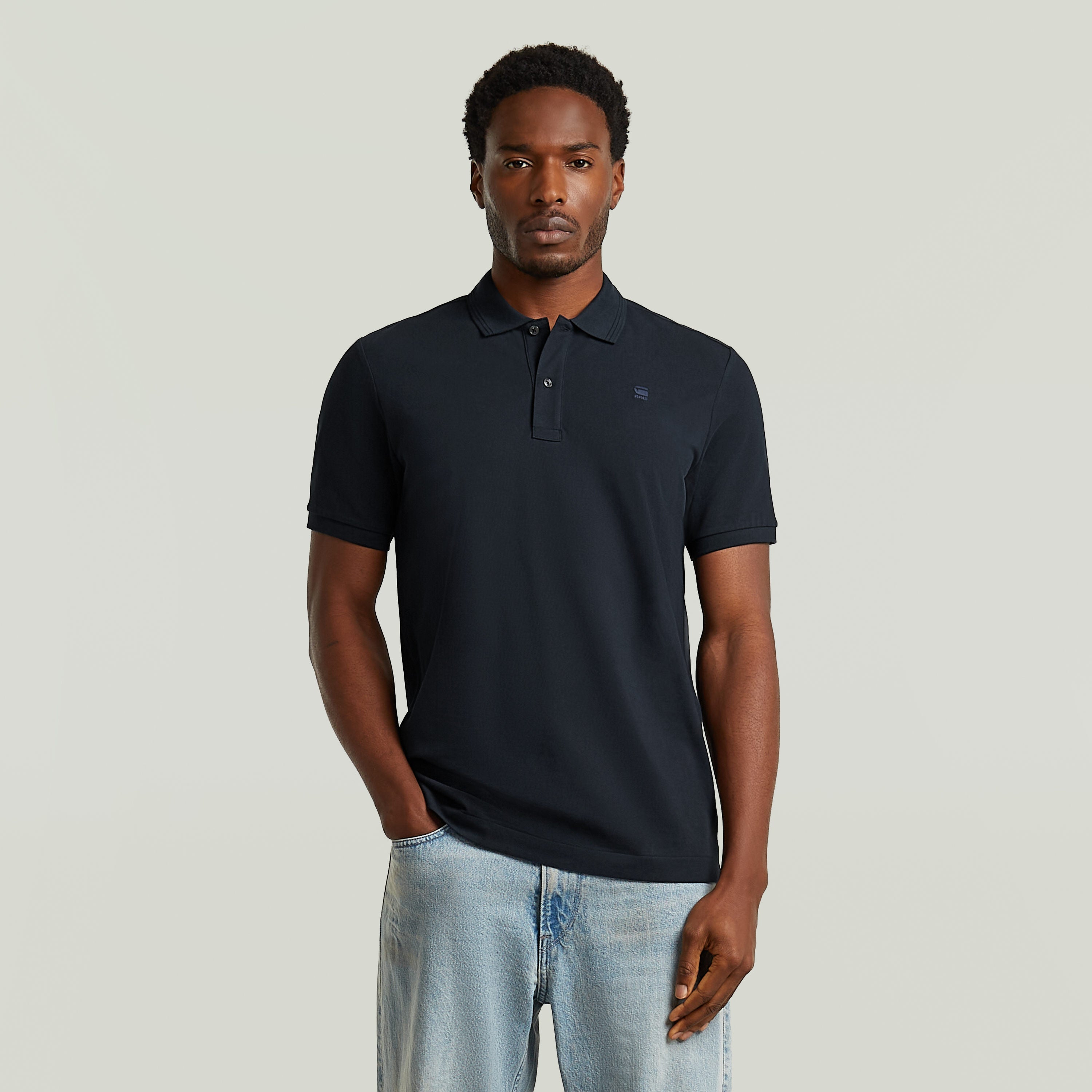 Modelo vistiendo un polo Dunda Slim fit polo shirt en color azul oscuro, con corte ajustado y detalles sutiles.