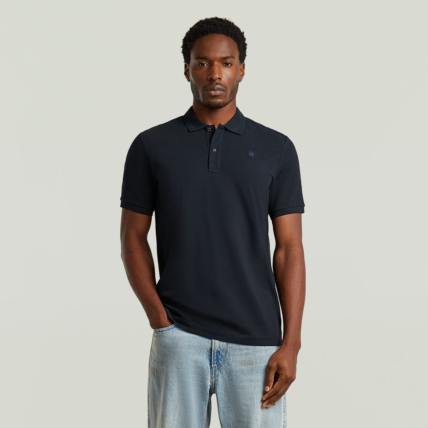 Modelo vistiendo un polo Dunda Slim fit polo shirt en color azul oscuro, con corte ajustado y detalles sutiles.