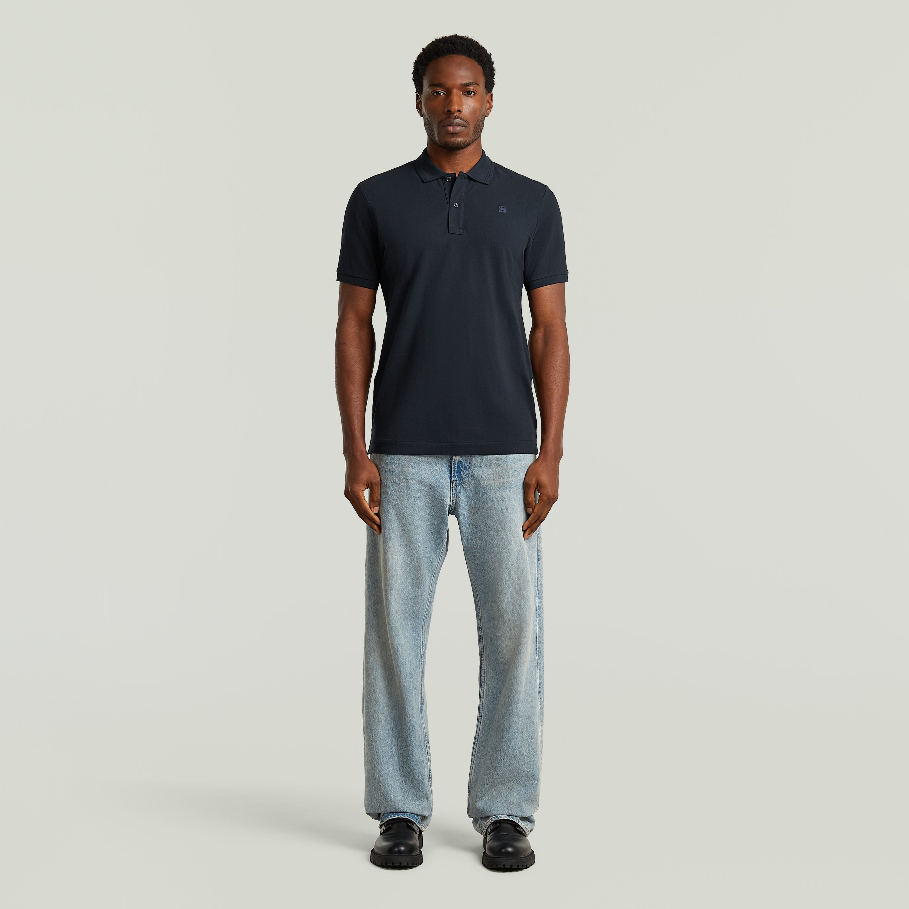 Modelo usando Polo Dunda Slim fit polo shirt color azul oscuro, combinado con jeans y calzado negro.