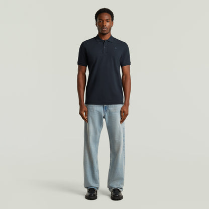 Modelo usando Polo Dunda Slim fit polo shirt color azul oscuro, combinado con jeans y calzado negro.