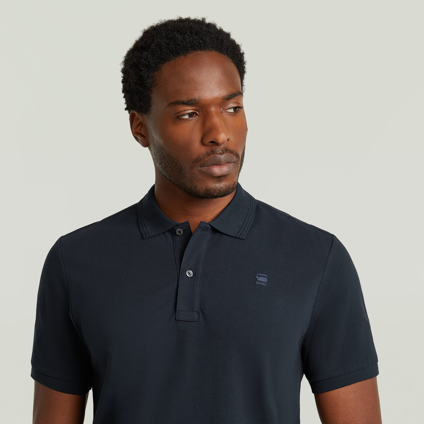 Hombre usando un polo Dunda Slim fit polo shirt en color azul oscuro, con corte ajustado y cierre de botones.