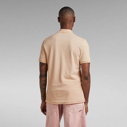 Hombre de espaldas vistiendo el polo Dunda Slim con cuello acanalado en color beige.