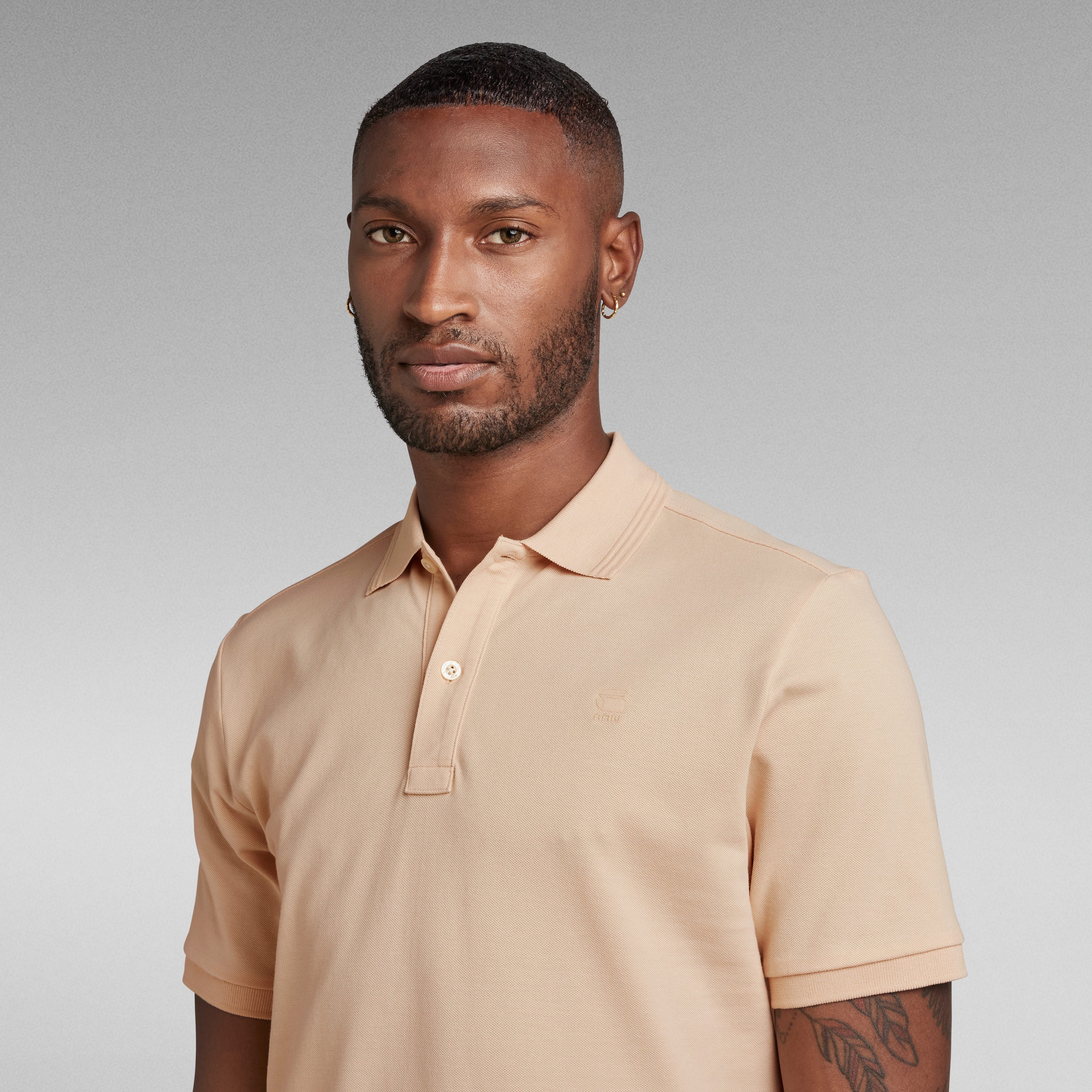 Modelo luciendo el polo Dunda Slim con ribbed collar en color beige, destacando su diseño elegante.