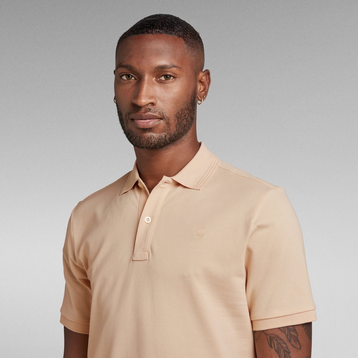 Modelo luciendo el polo Dunda Slim con ribbed collar en color beige, destacando su diseño elegante.