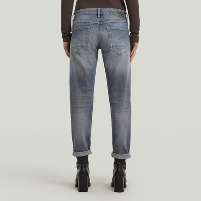 Back view of low rise boyfriend jeans with relaxed fit and rolled hem in light blue.