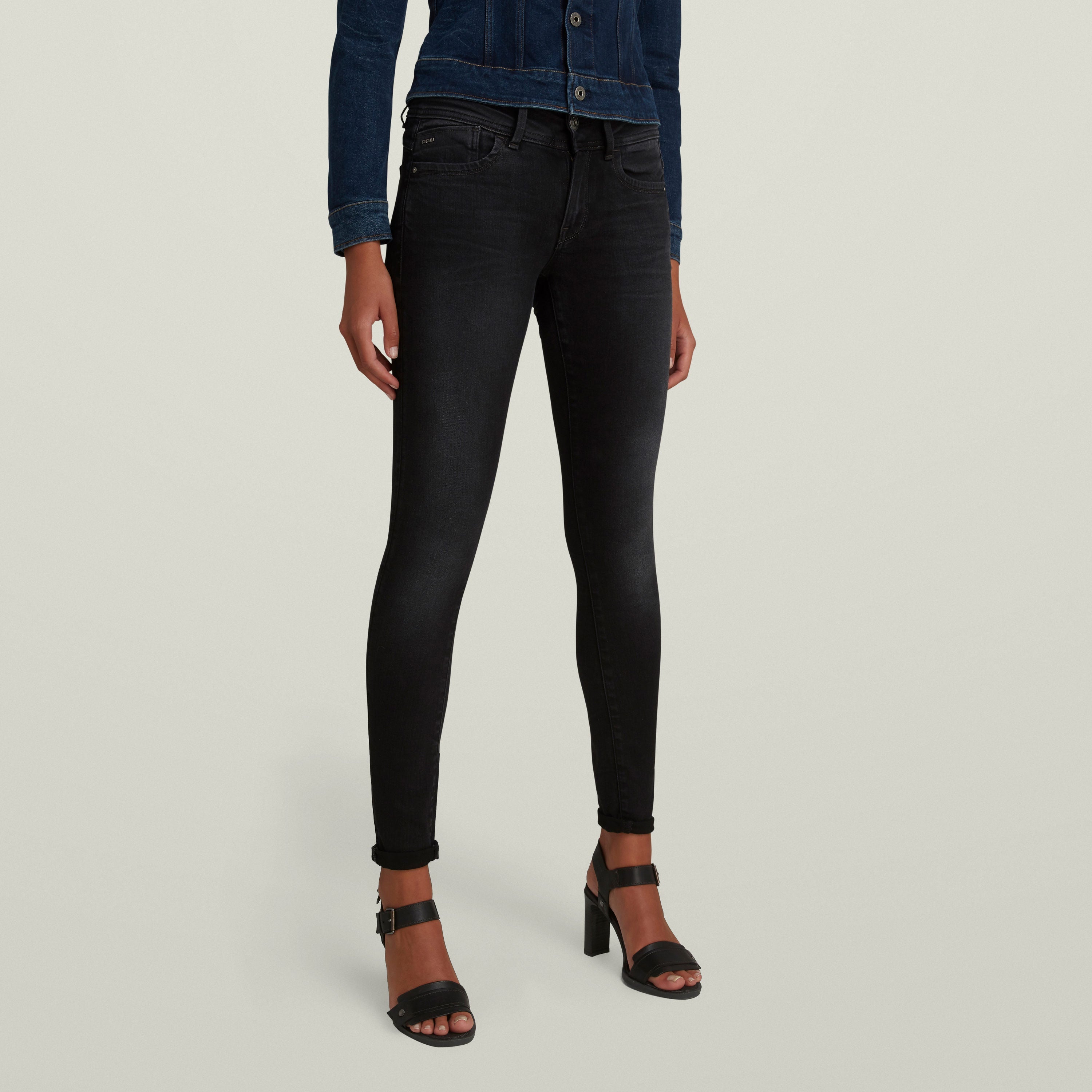 Black super skinny jeans for women, styled with high heels and a denim jacket for a chic look.