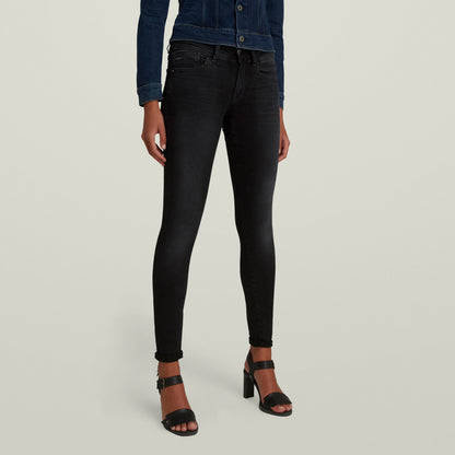 Black super skinny jeans for women, styled with high heels and a denim jacket for a chic look.