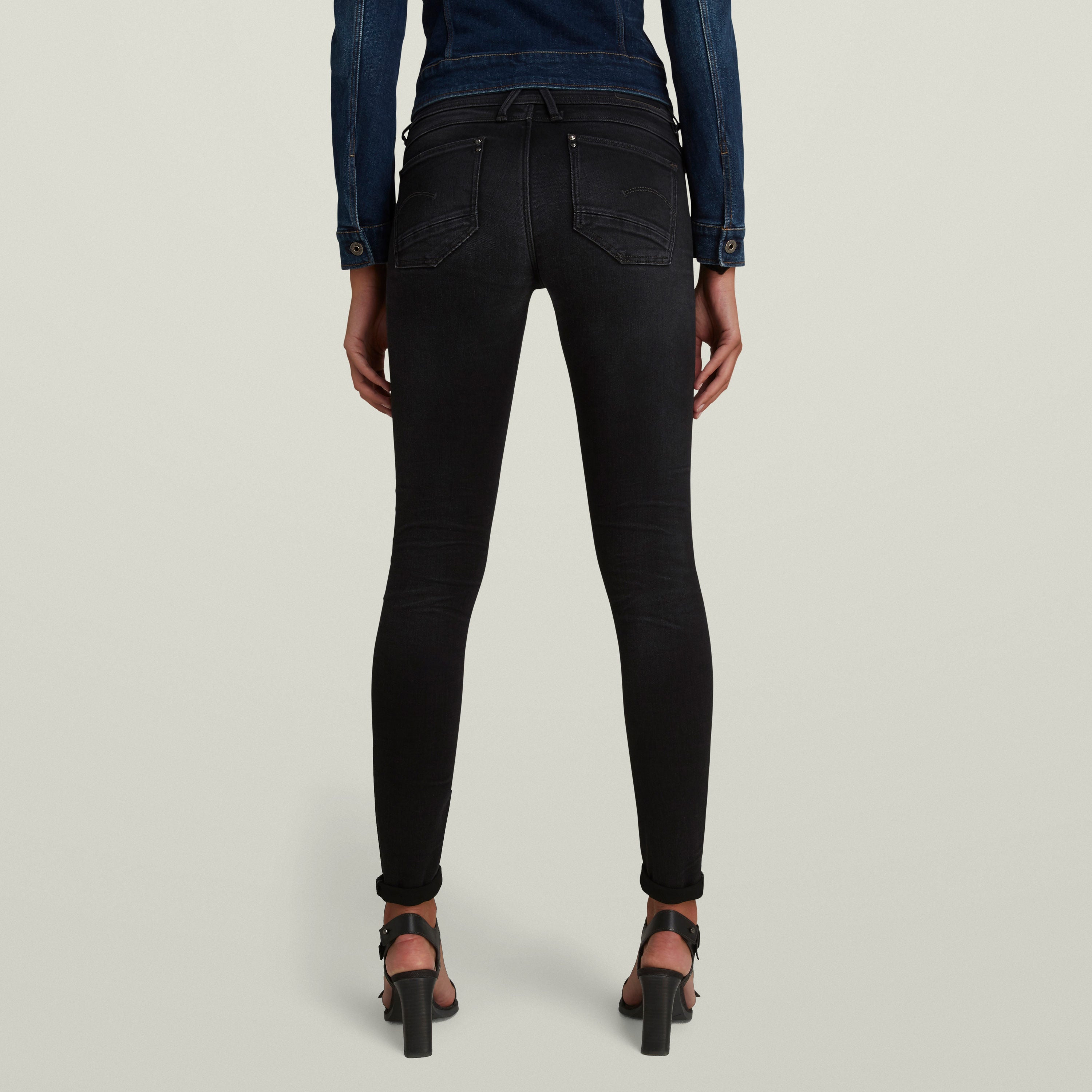 Mujer usando Jeans Lynn Super Skinny negros, vista trasera, mostrando la forma ajustada de los super skinny jeans for women.