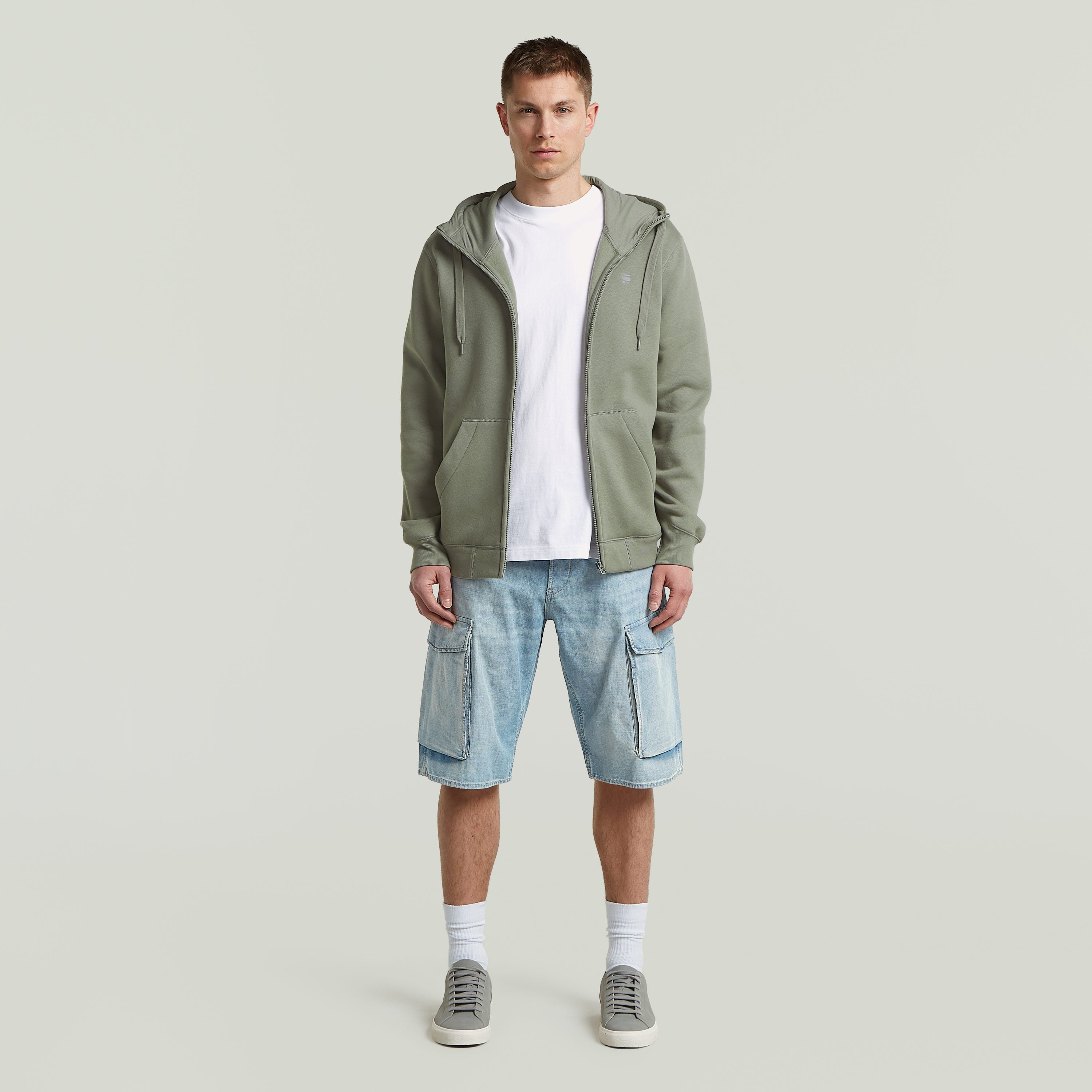 Modelo masculino usando sudadera premium hooded zip sweatshirt con pantalones cortos y zapatillas deportivas.