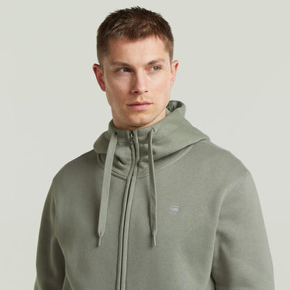 Hombre usando sudadera premium hooded zip sweatshirt con capucha y cremallera en color verde.