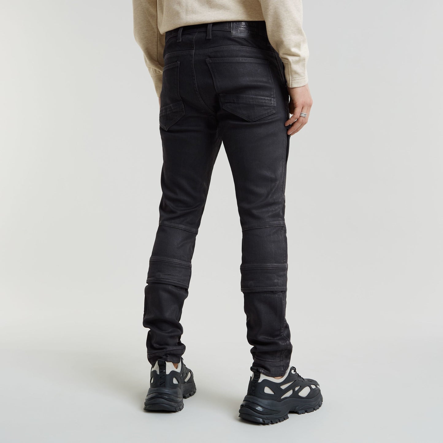 Mujer usando jeans Airblaze 3D skinny, corte pitillo negro, vistos desde atrás, con detalles en la pierna.
