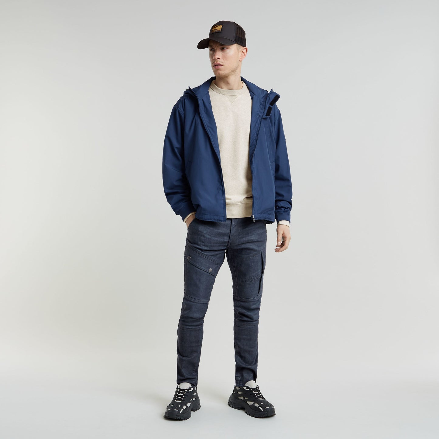 Hombre usando jeans Airblaze 3D skinny jeans for men, chaqueta azul y zapatillas negras, en fondo neutral.