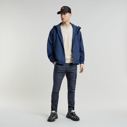 Hombre usando jeans Airblaze 3D skinny jeans for men, chaqueta azul y zapatillas negras, en fondo neutral.