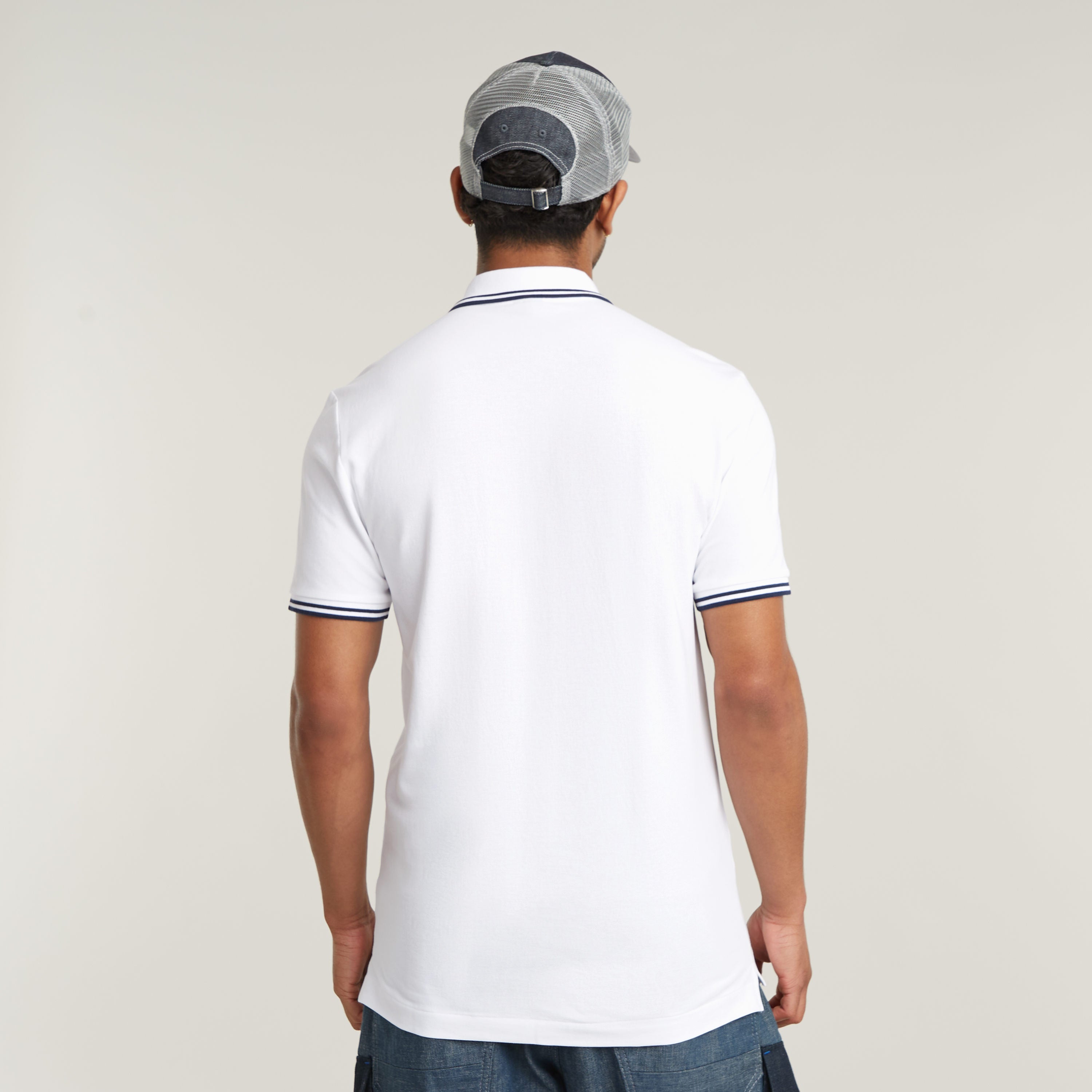 Hombre de espaldas usando el polo Dunda Slim Stripe, mostrando el diseño de cuello y puños del slim stripe polo shirt.