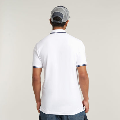 Hombre de espaldas usando el polo Dunda Slim Stripe, mostrando el diseño de cuello y puños del slim stripe polo shirt.