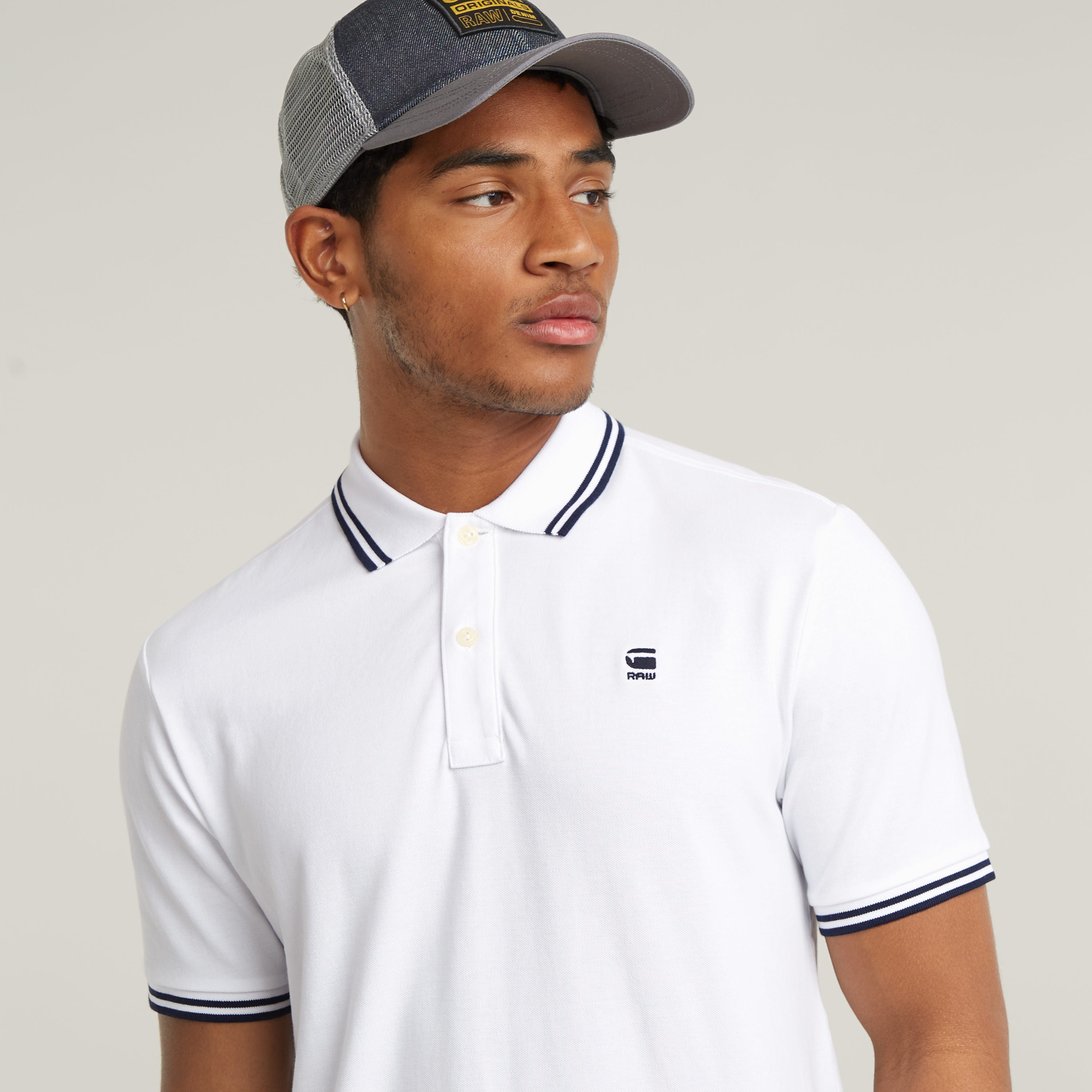 Slim stripe polo shirt on a model wearing a cap, showcasing a modern fitted design and striped details.