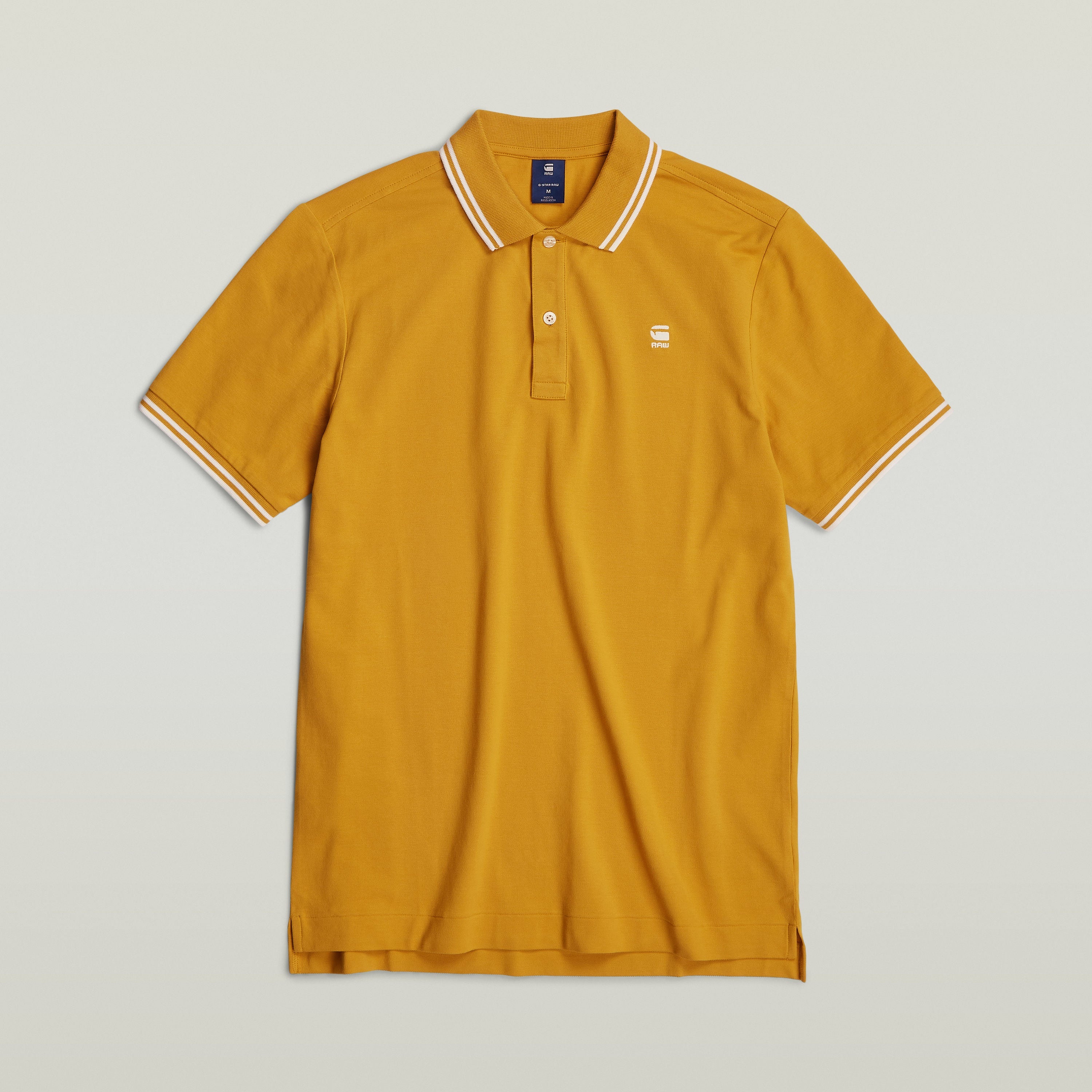 Polo Dunda Slim Stripe, un slim stripe polo shirt de color mostaza con detalles en el cuello y puños.