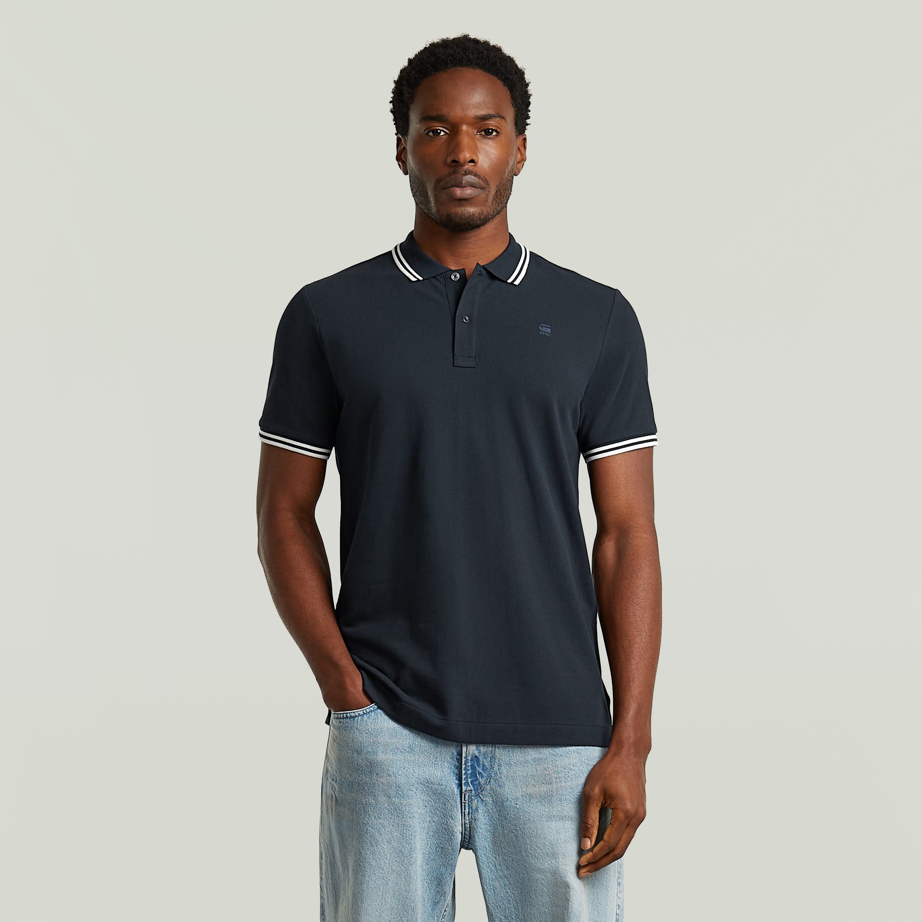 Modelo luciendo una camiseta polo slim stripe con diseño clásico en color azul oscuro y detalles en el cuello.