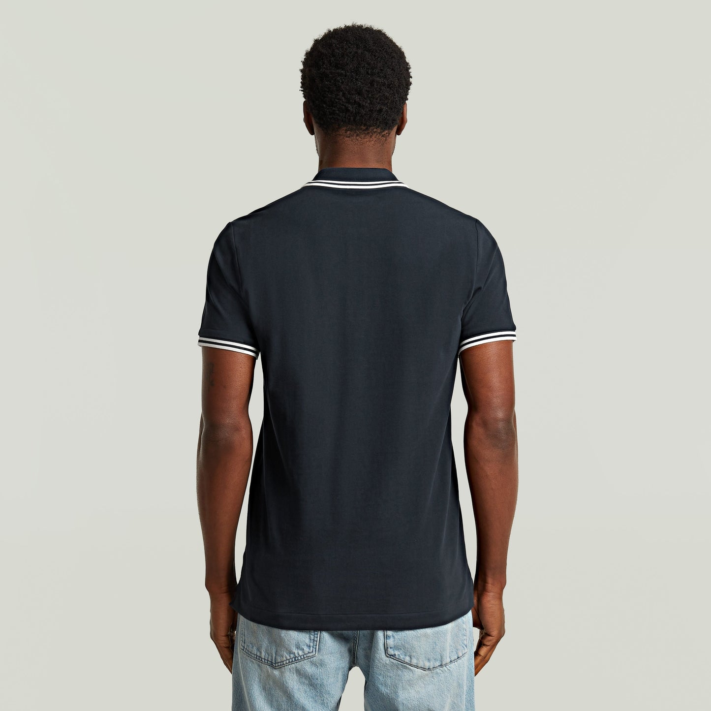 Back view of the Polo Dunda Slim Stripe, a slim stripe polo shirt in dark blue with stylish details.