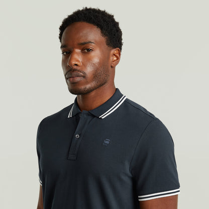 Modelo usando un polo Dunda Slim Stripe, camiseta slim stripe polo shirt, color azul oscuro con detalles en el cuello.