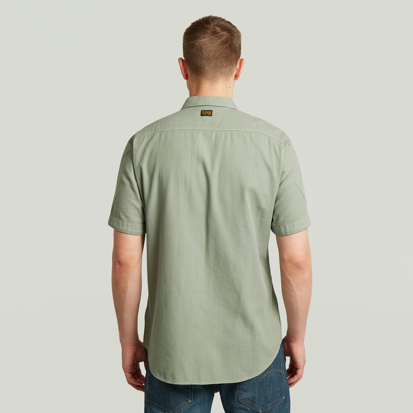 Hombre de espaldas con la camisa Marine Slim fit, color verde, corte ajustado y con bajo redondeado.