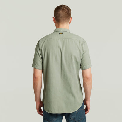 Hombre de espaldas con la camisa Marine Slim fit, color verde, corte ajustado y con bajo redondeado.
