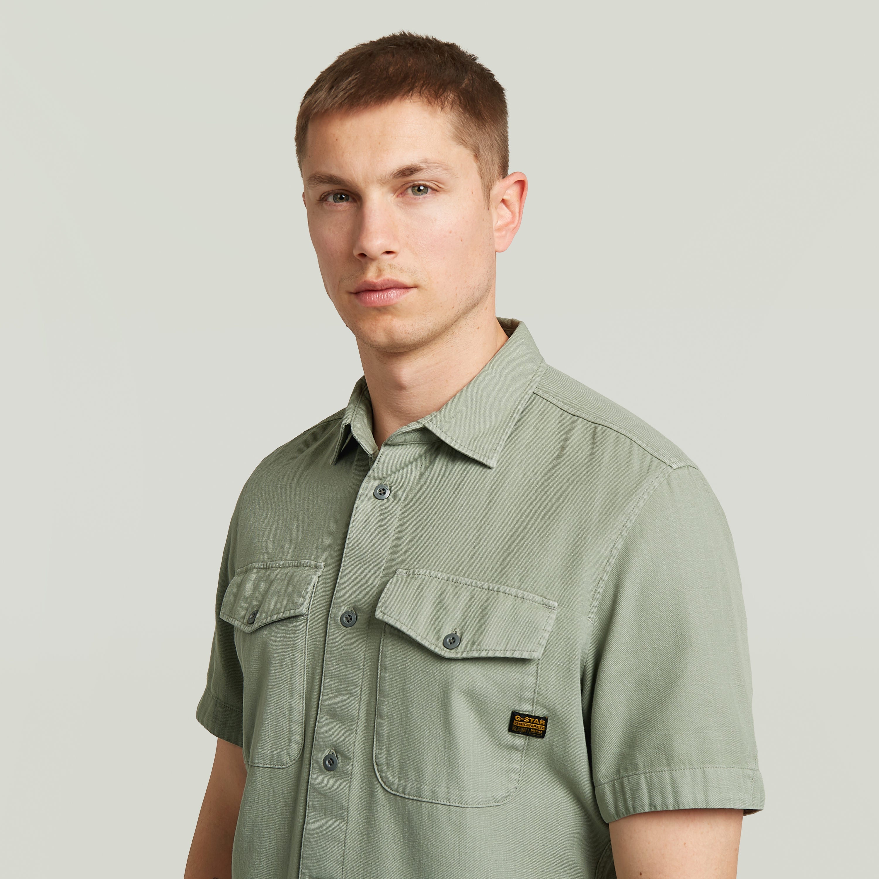 Hombre usando una camisa Marine Slim fit shirt verde con bolsillos en el pecho y cierre de botones.