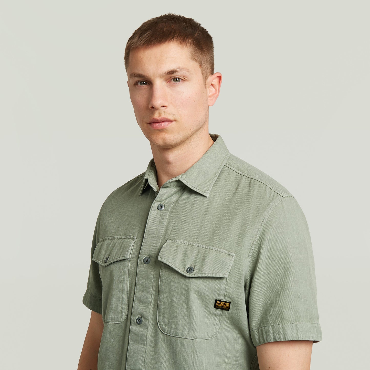 Hombre usando una camisa Marine Slim fit shirt verde con bolsillos en el pecho y cierre de botones.