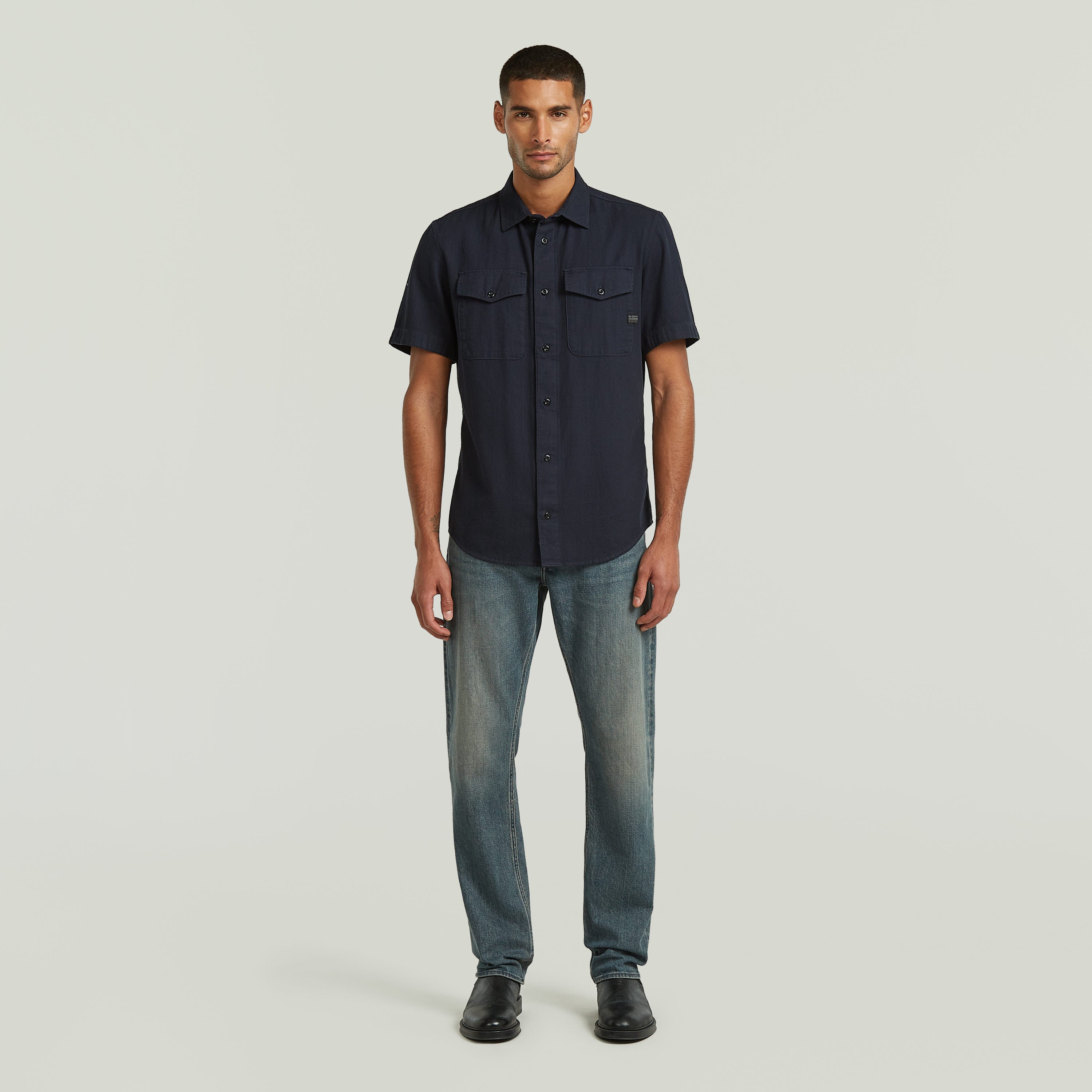 Hombre usando una camisa Marine slim azul con jeans, muestra el diseño ajustado y los bolsillos en el pecho.